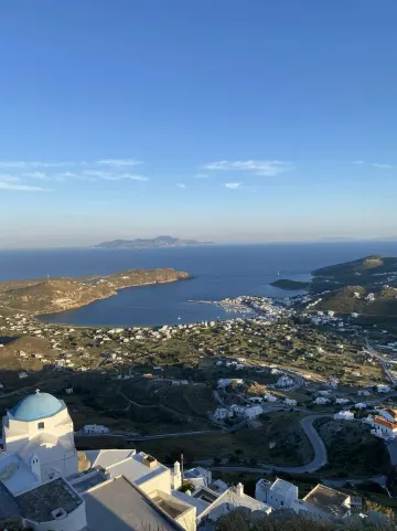 Baie et village blanc des Cyclades vus des hauteurs, dôme bleu d'une chapelle au premier plan, Grèce