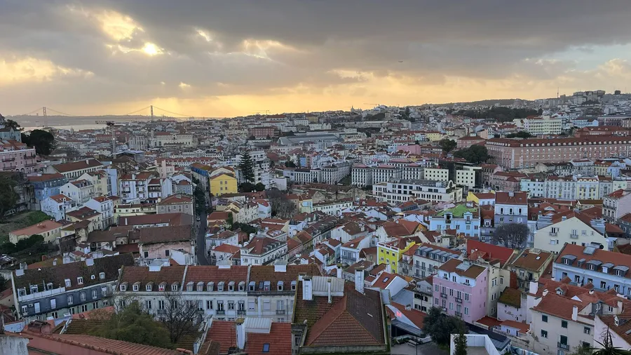 Toits de Lisbonne au couchant vus d'un belvédère, le Tage à l'horizon