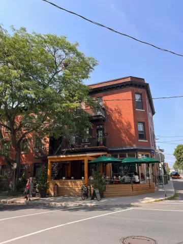 Immeuble de brique rouge et terrasse de café aux parasols verts sur le Plateau, Montréal