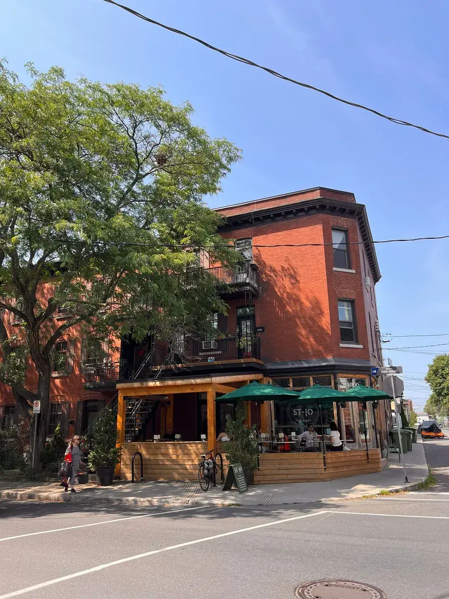 Immeuble de brique rouge et terrasse de café aux parasols verts sur le Plateau, Montréal